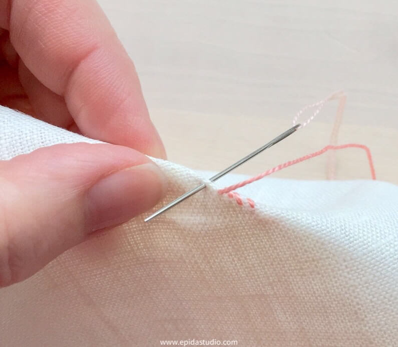 overcast stitch with pink thread on white fabric.