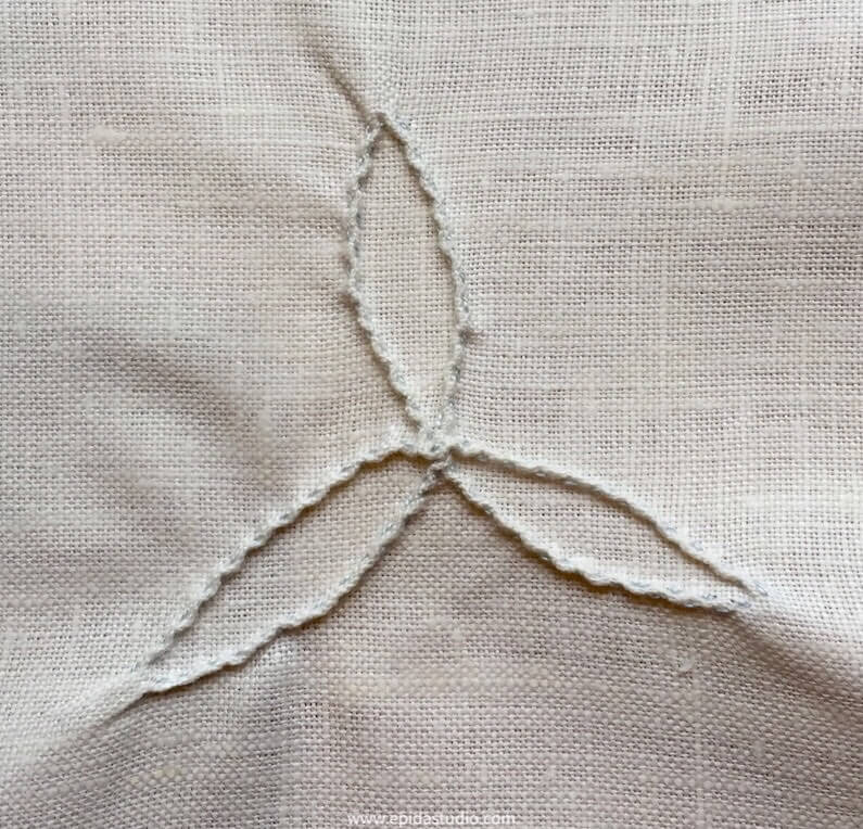 design stitched in running pinch stitch on white fabric.