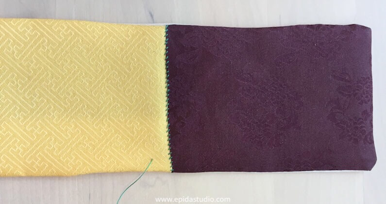yellow and purple fabric being stitched with green thread.