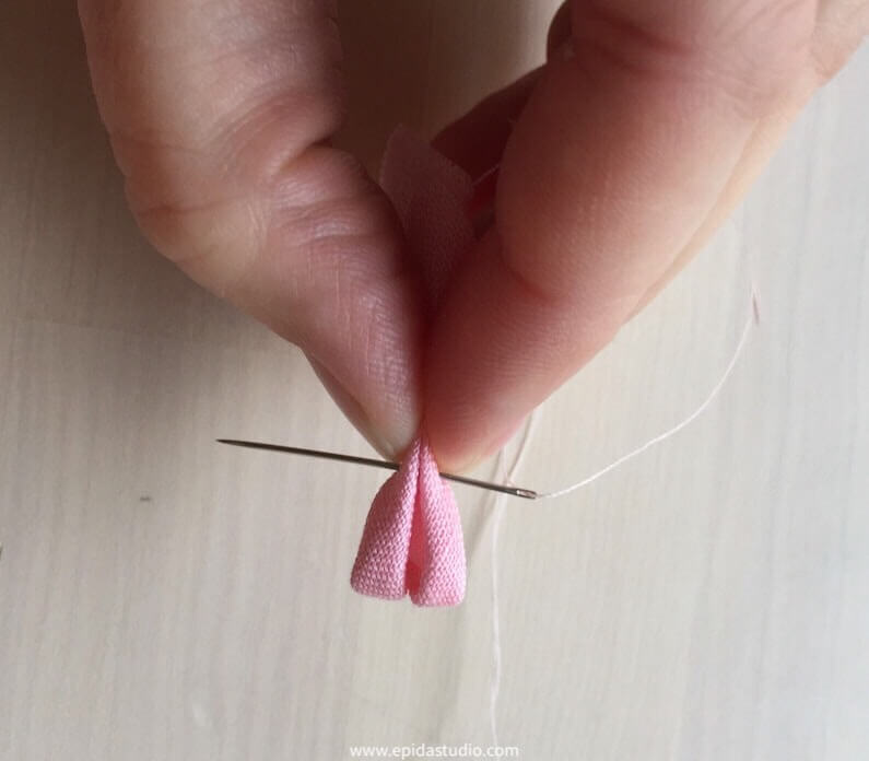 rolls of fabric being tacked with a needle and thread.