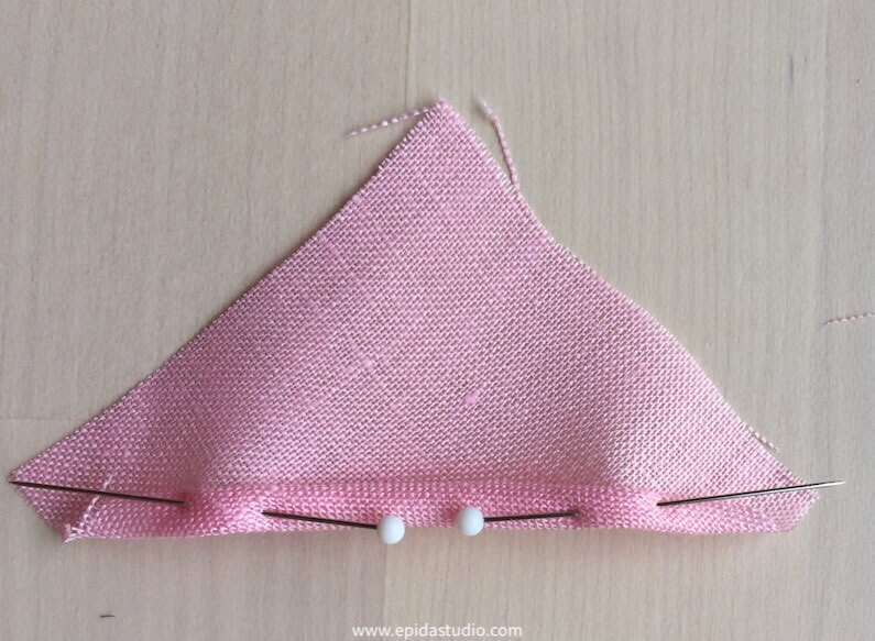 half square of fabric rolled and held with pins.