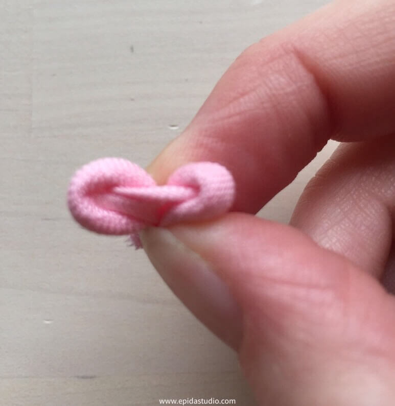 fingers holding fabric rolls being opened to make a flower.