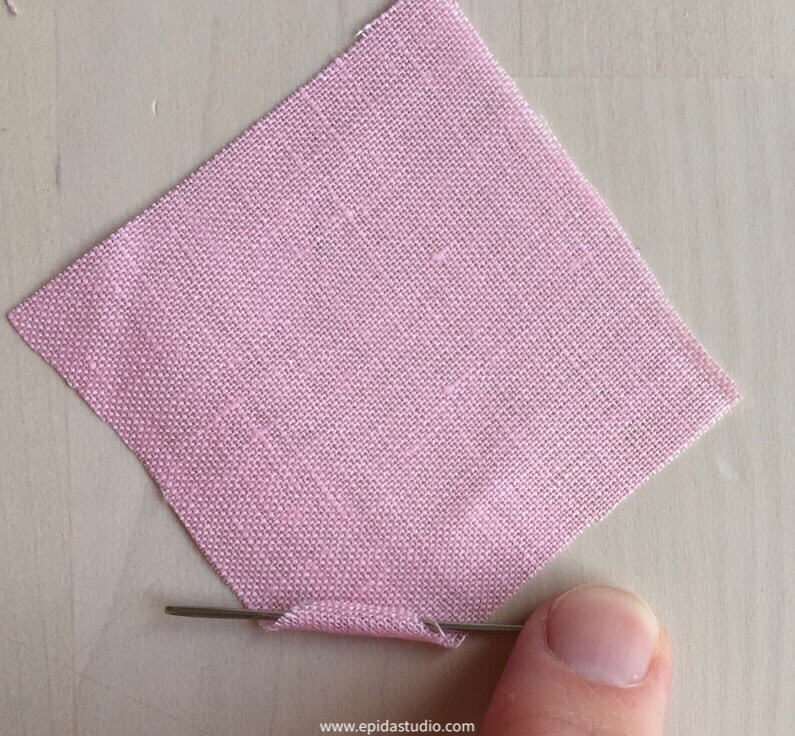 fabric being rolled on a needle.
