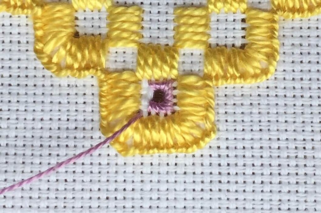 stitching an eyelet in hardanger embroidery.