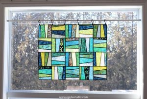 fabric window hanging in greens that looks like stained glass.