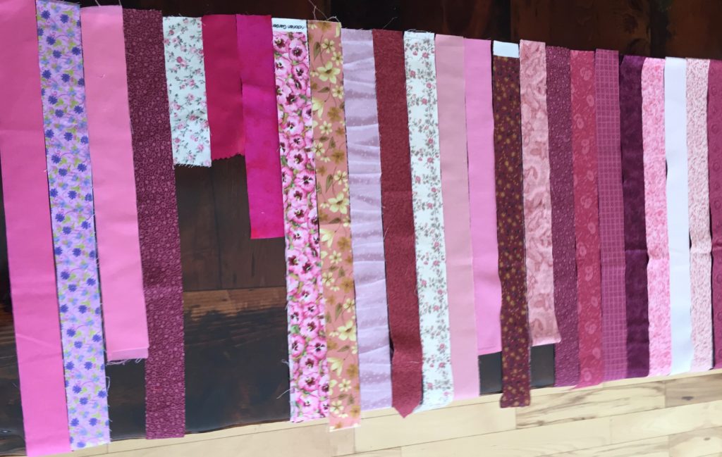 strips of pink fabric layer out for patchwork