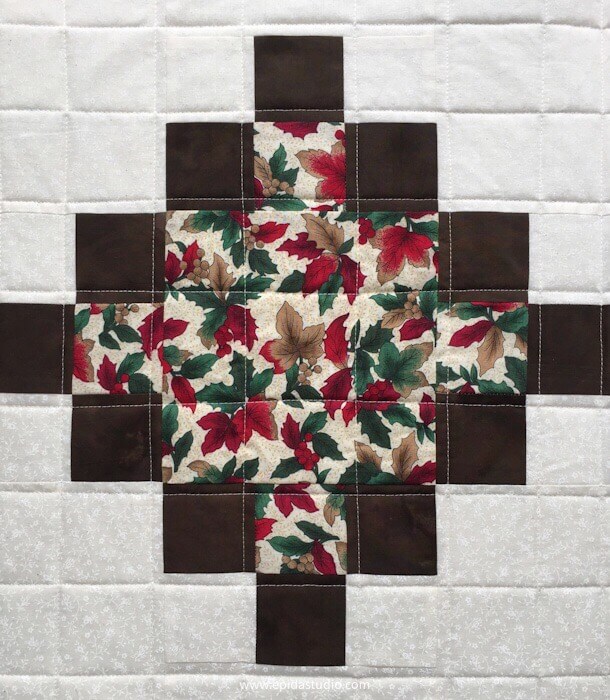quilt with brown squares surrounding a red and green floral print
