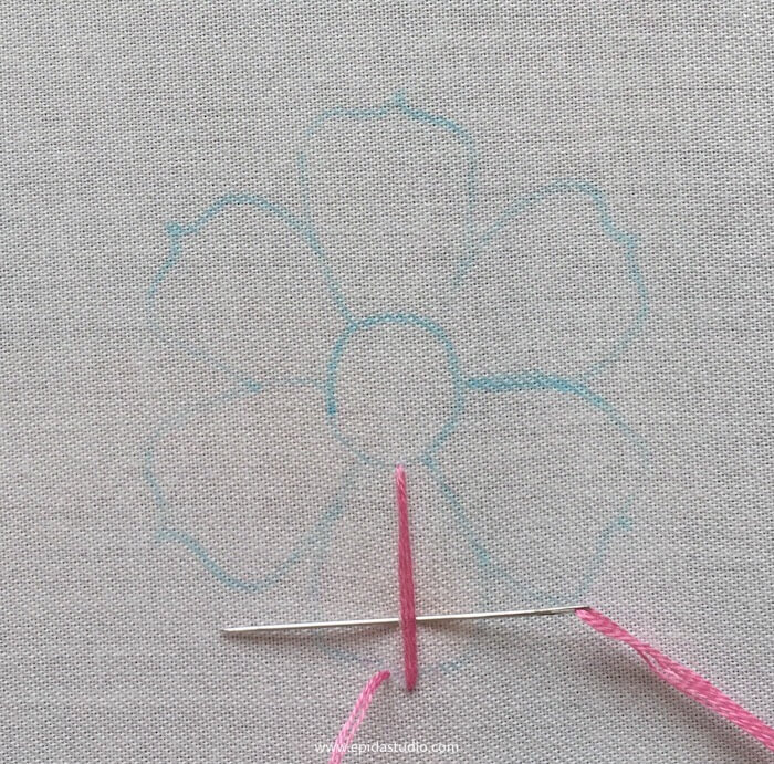 needle taking a stitch with pink floss