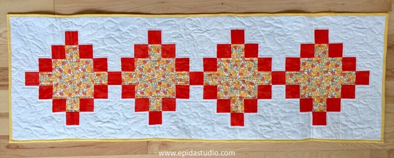quilted table runner with orange and yellow diamonds.