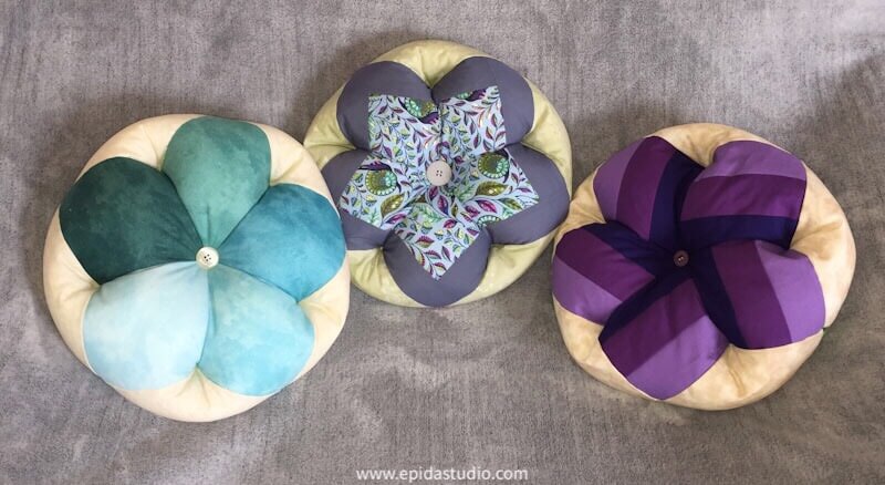 three throw pillows on a grey background.
