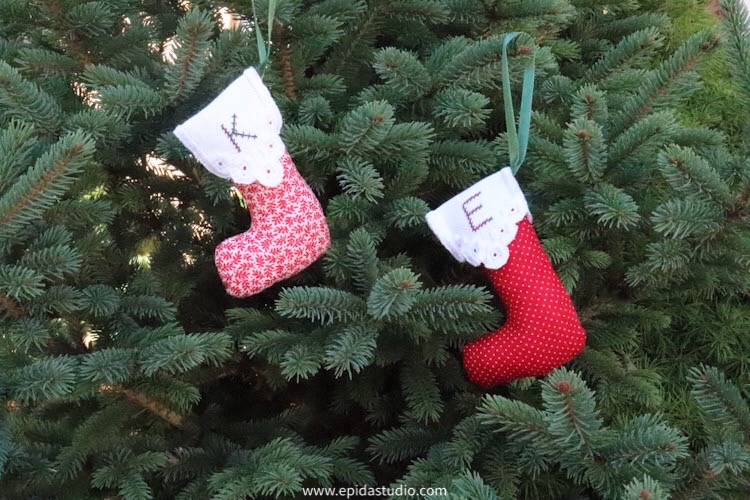 two embroidered Christmas ornaments hanging on a tree.