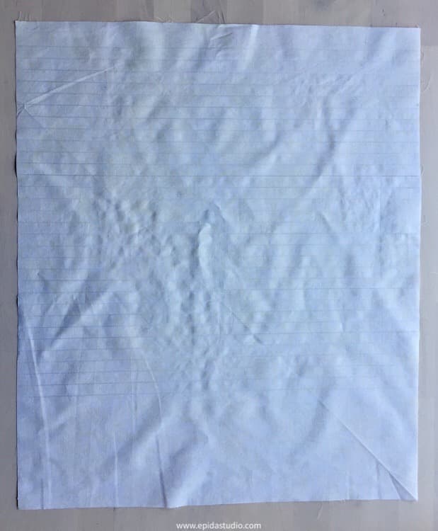 parallel lines marked on white fabric with pencil.
