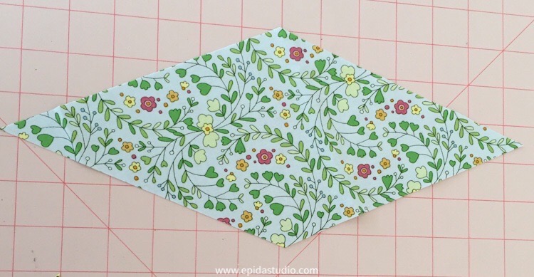 floral fabric diamond on pink cutting mat.