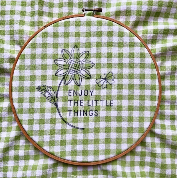 fabric in embroidery hoop with marked flower design.