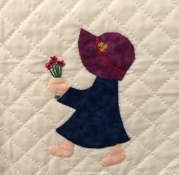 applqued sunbonnet sue with embroidered flowers.